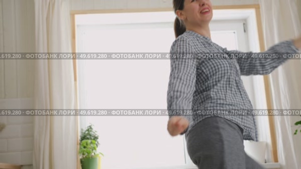 Brunette woman dance, have fun at home listens song, moves to music, feels overjoyed, celebrate good news, relish carefree life looks happy. Young adult female twirls, grooves. Lady dancing in kitchen. Стоковое видео, видеограф Марина Демидюк / Фотобанк Лори