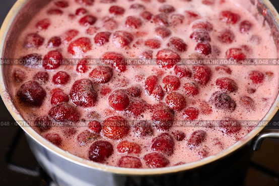 Bubbling red strawberry berries create a vibrant mixture as they simmer in a pot. Стоковое фото, фотограф Виктория Тельминова / Фотобанк Лори