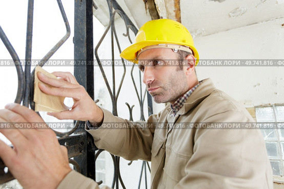 builder sanding a metal fence. Стоковое фото, агентство Ingram Publishing / Фотобанк Лори