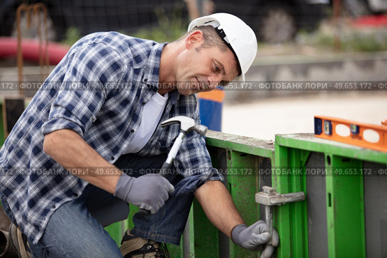 builder worker with hammer at construction site. Стоковое фото, агентство Ingram Publishing / Фотобанк Лори