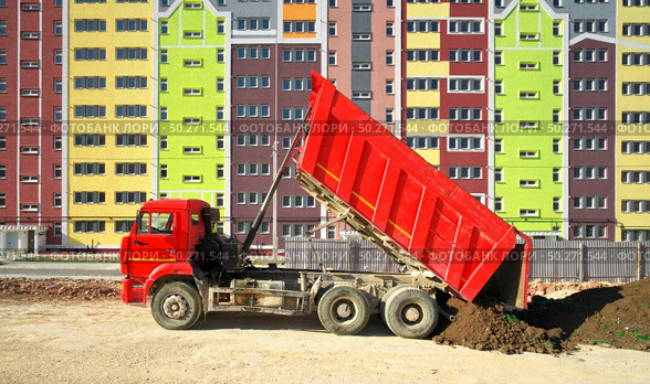 Building urban scene. Multistorey building apartment house and dump truck unload soil at day. Стоковое фото, агентство Ingram Publishing / Фотобанк Лори