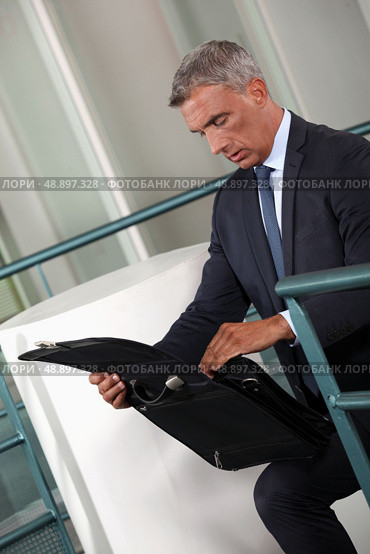 Businessman rummaging thought his briefcase. Стоковое фото, агентство Ingram Publishing / Фотобанк Лори