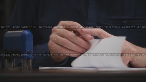 Businessman working on paperwork and stamping approvals, signing documents. close up male hands signing a contract, an agreement. paperwork documentation concept. front view. Стоковое видео, видеограф ЛУНИНА ВЕРОНИКА / Фотобанк Лори
