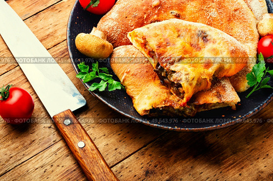 Calzone, a closed pie with vegetable filling. Dish of italian cuisine. Calzone - Italian pie, pizza. Стоковое фото, агентство Ingram Publishing / Фотобанк Лори