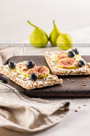 Canape or crostini with multigrain  crispread with cream cheese and fresh fig slices on a wooden board. Delicious appetizer ideal as an aperitif. Стоковое фото, агентство Ingram Publishing / Фотобанк Лори
