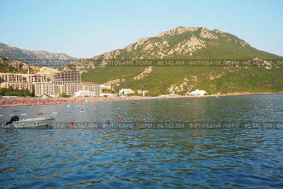 Canj, Montenegro 07.20.2024 Boats and a shore with vacationers, sunbathers and swimmers. Hotels, sun umbrellas, Adriatic waves, buoys. Beach tourism. Vacation travel. Summer day. Pebble rock beach. Редакционное фото, фотограф Юлия Петровская / Фотобанк Лори