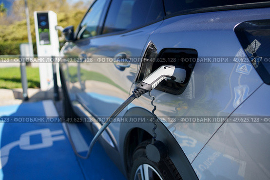 Car charging its electric battery at one charging point for electric vehicles located on the street.. Refueling an electric car, an environment friendly alternative. Стоковое фото, агентство Ingram Publishing / Фотобанк Лори