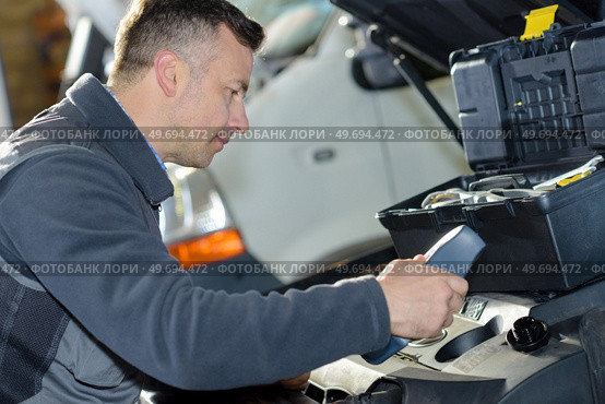 car mechanic replacing oil on engine in garage. Стоковое фото, агентство Ingram Publishing / Фотобанк Лори