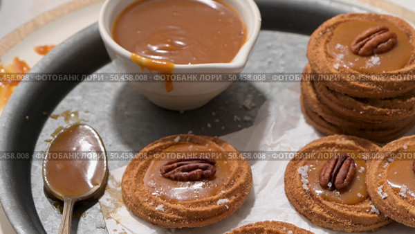 Caramel cookies with pecan nuts served on roud plates, in the kitchen after baking. Стоковое фото, агентство Ingram Publishing / Фотобанк Лори