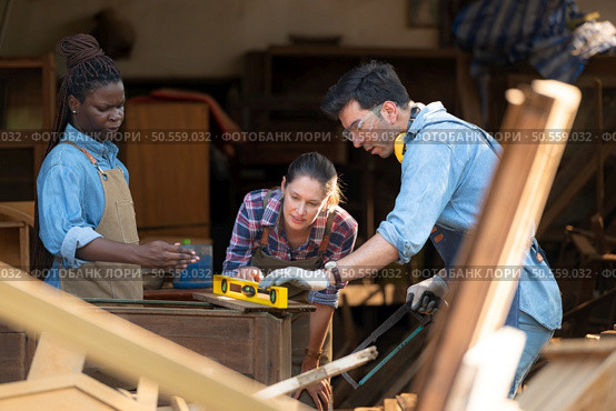 Carpenter and his assistant working together in a carpentry workshop. Стоковое фото, агентство Ingram Publishing / Фотобанк Лори