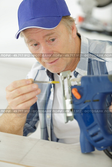 carpenter changes the nozzle in an electric jigsaw. Стоковое фото, агентство Ingram Publishing / Фотобанк Лори