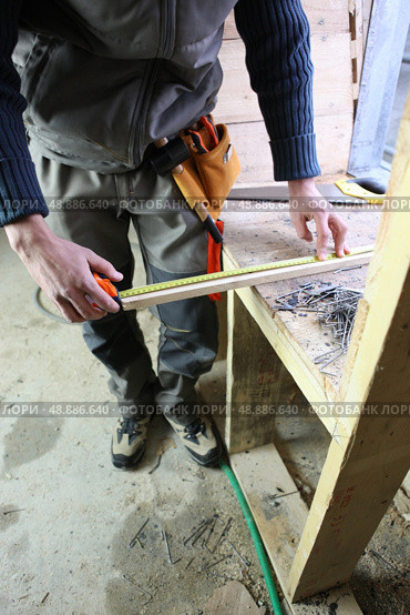 Carpenter measuring plank of wood. Стоковое фото, агентство Ingram Publishing / Фотобанк Лори