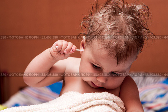 Caucasian baby picking his ear with cotton swab, child after bathing, disheveled hair. Стоковое фото, фотограф Кекяляйнен Андрей / Фотобанк Лори