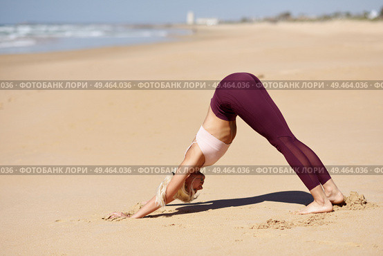 Caucasian woman practicing yoga at seashore. Young female doing downward-facing dog in the beach in Cadiz, Andalusia, Spain.. Caucasian blonde woman practicing yoga in the beach. Стоковое фото, агентство Ingram Publishing / Фотобанк Лори