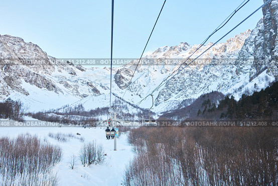 Cei, Russia. - January 06, 2024: A ski lift is visible against the background of a snow-covered mountain. The ski lift is surrounded by trees and snow. Редакционное фото, фотограф Наталия Кирсанова / Фотобанк Лори