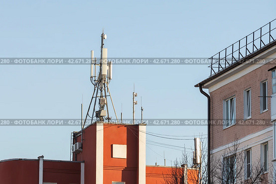 Cell phone towers on the roof of a building near residential buildings, a concept on the topic of the dangerous effects of radio waves on human health. Стоковое фото, фотограф Сергей Чайко / Фотобанк Лори