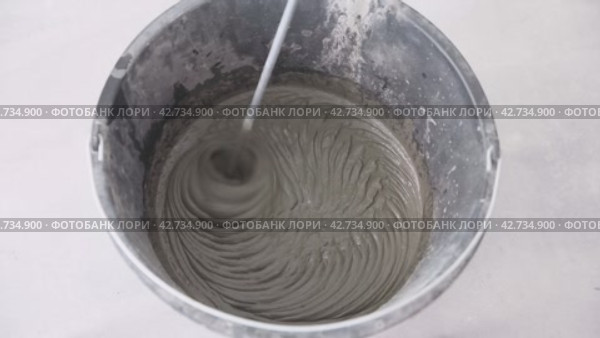 Cement mortar is mixed with a mixer in a building bucket. Concrete and finishing works. Preparation of adhesive solution. Стоковое видео, видеограф Дмитрий Кобзев / Фотобанк Лори