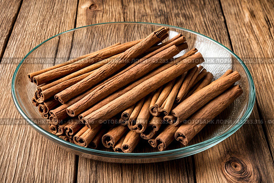 Ceylon cinnamon sticks in glass plate on wooden board, rustic style. Still life natural food of sri lankan cinnamon sticks on table at grey wall. Delicious tasty healthy concept. Copy ad text space. Стоковое AI-изображение, AI-художник Aleksandr Golubev / Фотобанк Лори