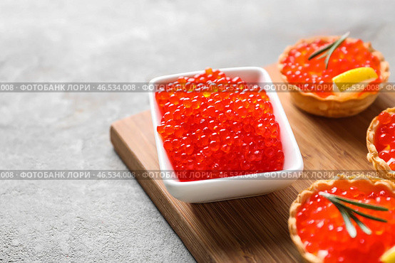 Чаша с вкусной красной икрой и канапе на деревянной доске, крупным планом. Стоковое фото, фотограф Pixel_shot / Фотобанк Лори