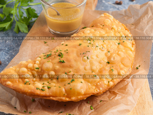 Cheburek with meat and mustard dressing, decorated with greens on parchment. Стоковое фото, фотограф Дмитрий Ульянов / Фотобанк Лори