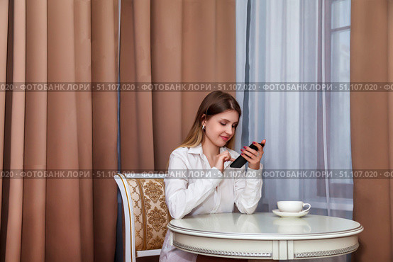 Checking Her Phone in a Serene Hotel Room in the Afternoon. Стоковое фото, фотограф Aleksandr Golubev / Фотобанк Лори
