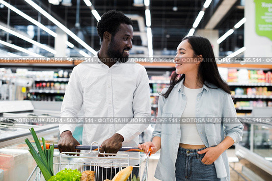cheerful multiracial couple with shopping cart supermarket. Стоковое фото, агентство Ingram Publishing / Фотобанк Лори