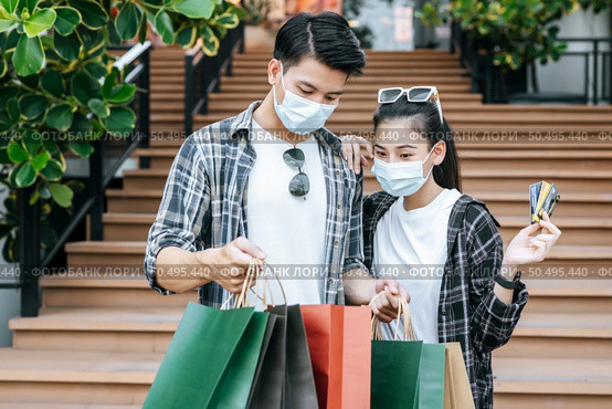 Cheerful Young couple holding multiple paper shopping bag going down stairs of large shopping mall and pretty woman show credit card in hand, They look inside bag with excited. Стоковое фото, агентство Ingram Publishing / Фотобанк Лори