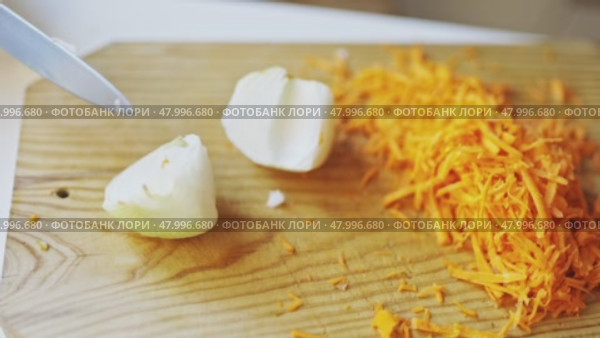 Chef chopping onion next to grated carrots on wooden cutting board. Стоковое видео, видеограф Константин Шишкин / Фотобанк Лори
