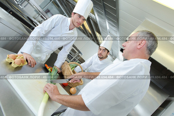 chef talking to trainees while demonstration how to chop leeks. Стоковое фото, агентство Ingram Publishing / Фотобанк Лори