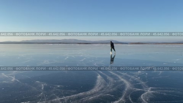 Человек катается на коньках на замёрзшем озере с прозрачным льдом в ясный солнечный морозный день. Стоковое видео, видеограф Светлана Акифьева / Фотобанк Лори