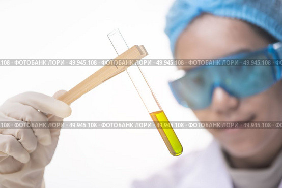 Chemical laboratory scene: attractive young PhD student scientist observing the indicator color shift in the glass tube. Стоковое фото, агентство Ingram Publishing / Фотобанк Лори