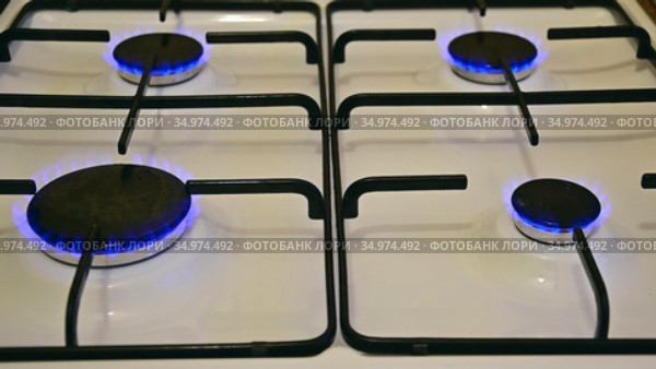 Четырехконфорочная газовая плита с горящими конфорками. White enameled surface of a gas stove with four burning burners. Стоковое видео, видеограф Владимир Литвинов / Фотобанк Лори