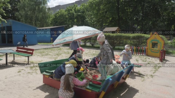 Children, boys and girls in kindergarten play in sand with toys on the street. Kids on playground in sandbox on sunny day: Gomel, Belarus - June 2021. Редакционное видео, видеограф Дмитрий Нечаев / Фотобанк Лори