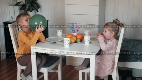 Children Drinking Juice on a Birthday Party at Home. Siblings, girls and a boy together celebrating a party, eating cake sitting at festive table. Little Kid Celebration. Surprise. Low key. Стоковое видео, видеограф Марина Демидюк / Фотобанк Лори