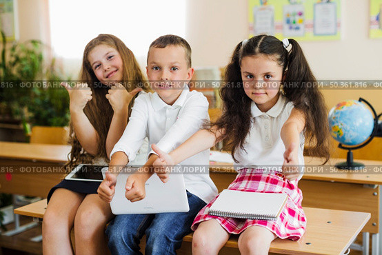 children sitting school desk gesturing. Стоковое фото, агентство Ingram Publishing / Фотобанк Лори