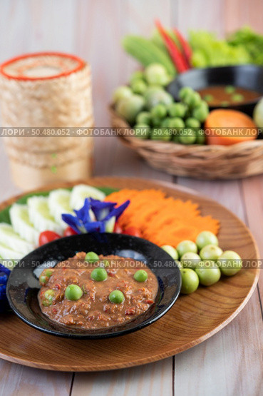 Chili paste paste in a bowl with eggplant, carrots, chili, cucumbers in a basket on wood table. Стоковое фото, агентство Ingram Publishing / Фотобанк Лори