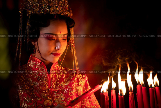 Chinese woman make wishes, pray, and light candles. On the occasion of the annual Chinese New Year festival, in a revered shrine or temple, And in Chinese where candles mean good luck and happiness. Стоковое фото, агентство Ingram Publishing / Фотобанк Лори