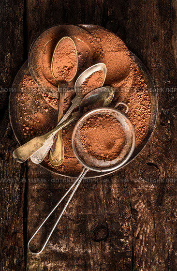 Chocolate powder with spoons and strainer on dark wooden background, top view. Стоковое фото, агентство Ingram Publishing / Фотобанк Лори