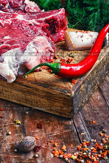 Chopped pieces of raw beef with spices on wooden cutting board. rib eye of beef. Стоковое фото, агентство Ingram Publishing / Фотобанк Лори
