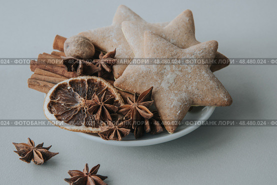 Christmas gingerbread in the shape of stars and spices on a saucer on a white table. Selective focus. Стоковое фото, фотограф София Тюленева / Фотобанк Лори