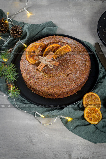 Christmas orange cake decorated with dried oranges on Christmas decorated kitchen countertop. Стоковое фото, агентство Ingram Publishing / Фотобанк Лори