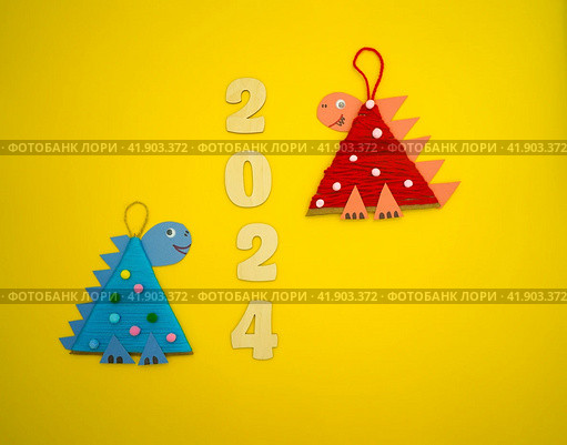 Christmas tree toys a dragon made by a child out of cardboard and threads lies on a yellow background. The symbol of 2024. Educational and craft activity. Стоковое фото, фотограф Ирина Старикова / Фотобанк Лори