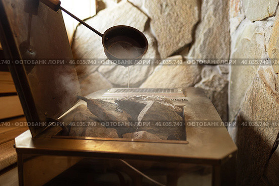 Close-up Hot stones in furnace for produce steam and heat in steam room. Steam an water on the stones, spa and wellness concept, relax in hot finnish sauna. Interior of wooden sauna. Стоковое фото, фотограф Сергей Тимофеев / Фотобанк Лори