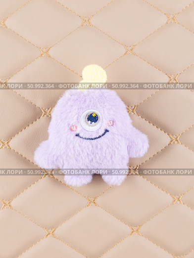 Close-up of a fluffy purple  monster plush toy with a playful smile and a small horn. Стоковое фото, фотограф Виталий Сова / Фотобанк Лори