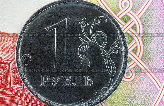 Close-up of a Russian one ruble coin against the background of a paper banknote. Concept of money, finance, cooperation, exchange rate and trade. Flat lay, macro, top view, mockup. Стоковое фото, фотограф Виктория Катьянова / Фотобанк Лори