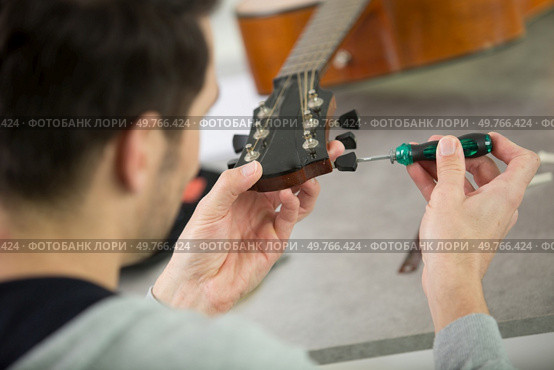 close up of man using a screw driver on guitar. Стоковое фото, агентство Ingram Publishing / Фотобанк Лори