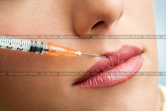 Close up of syringe injecting botox into female lips. Стоковое фото, агентство Ingram Publishing / Фотобанк Лори