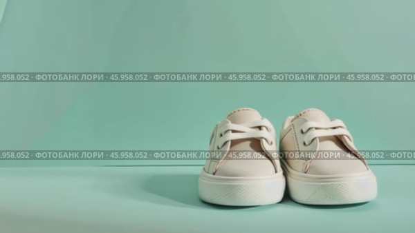 Close up of textile baby booties. Pregnancy concept, Pairs of baby shoes on a green background. Gender neutral baby garment and accessories. Organic newborn bootie, fashion, branding. Gender neutral. Стоковое AI-видео, аниматор Марина Демидюк / Фотобанк Лори