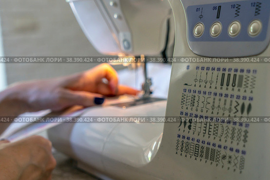 Close-up of the seamstress's hands at the sewing machine hem fabric, clothing. Стоковое фото, фотограф Игорь Кляхин / Фотобанк Лори
