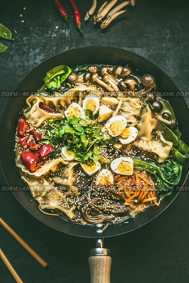 Close up of wok pan with vegetarian  korean hot pot and chopsticks on dark rustic kitchen table background, top view. Copy space. Asian food concept. Стоковое фото, агентство Ingram Publishing / Фотобанк Лори